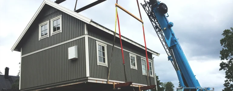 Kranbil lyfter ett hus på plats